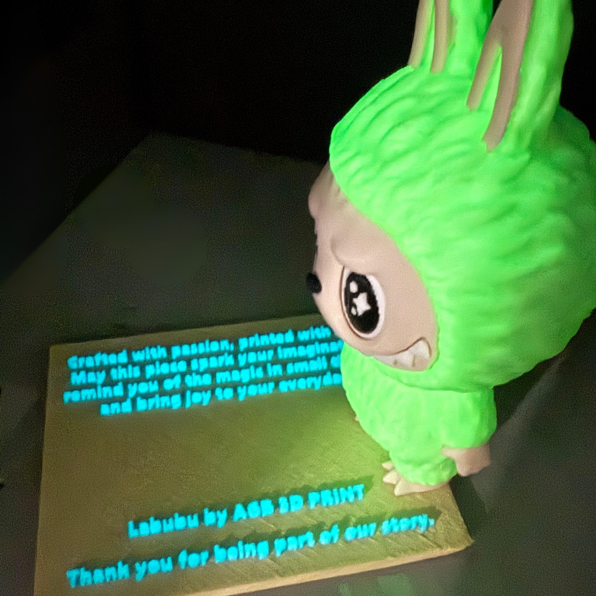 Side profile of glowing green Labubu 3D printed collectible showing textured fur and detailed face with glowing green suit.