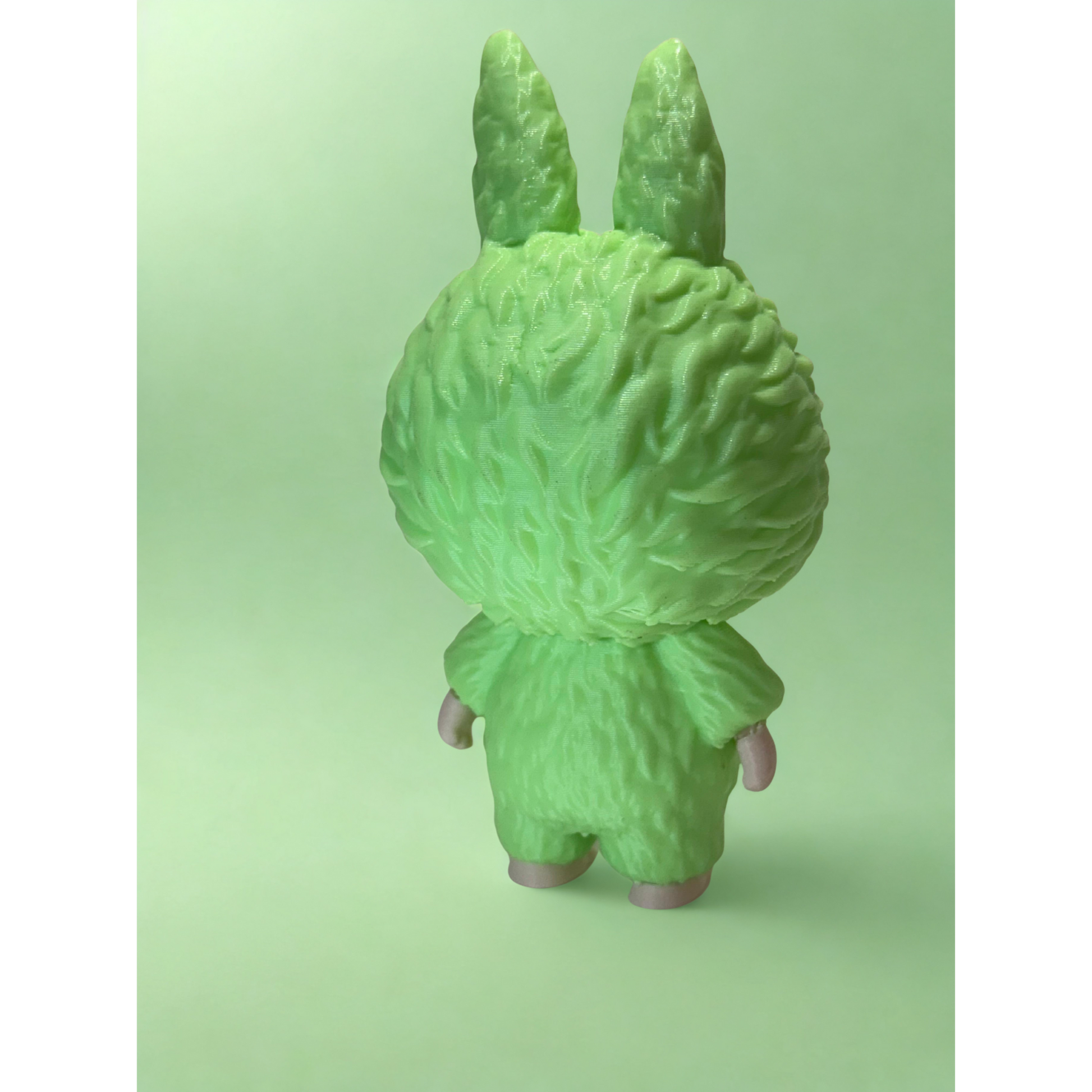Close-up of glowing green Labubu figurine radiating light in dark environment, showcasing glow-in-the-dark PLA material.